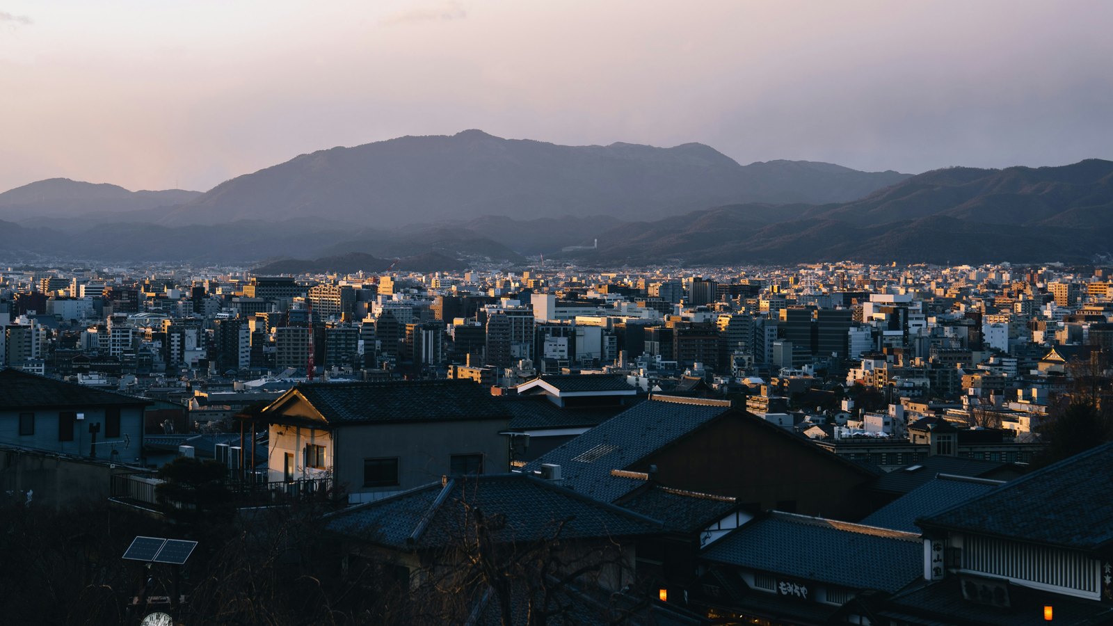 Japanese city and mountains at dusk, representing Pentos’s base in Japan.